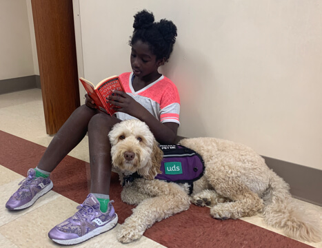 Girl reading to service dog