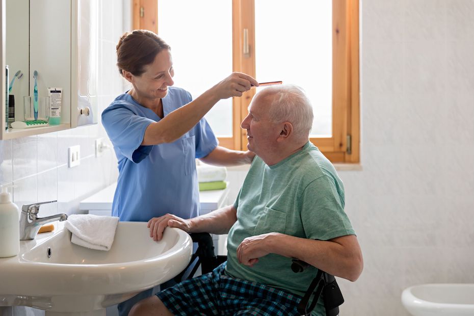 Caretaker brushing senior man's hair, this service is included in home health care