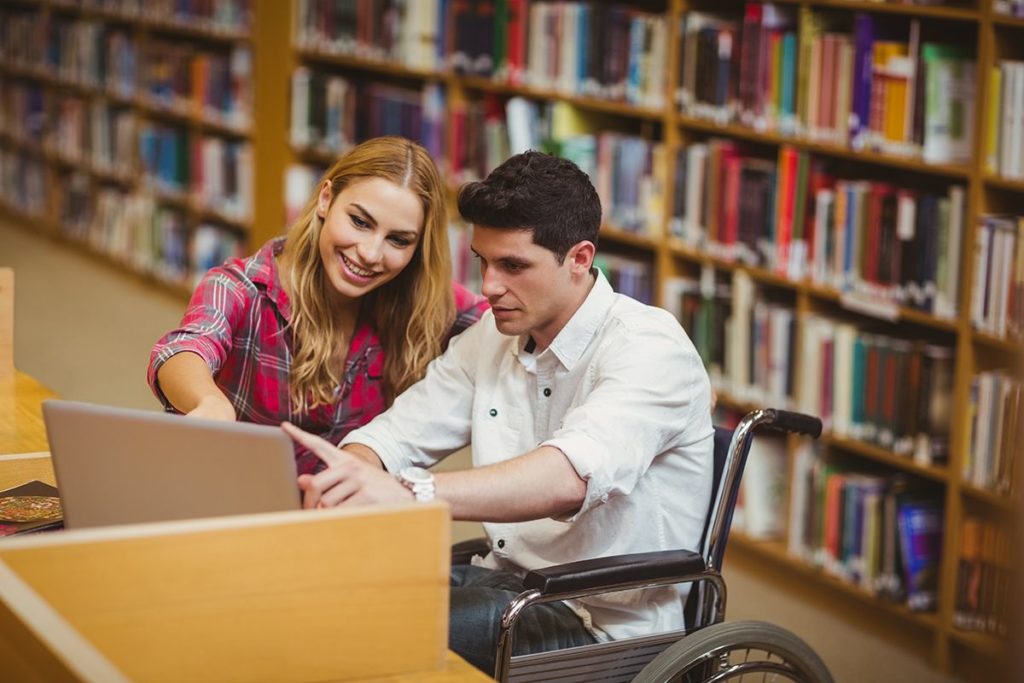 A student in a wheelchair studying in a library.