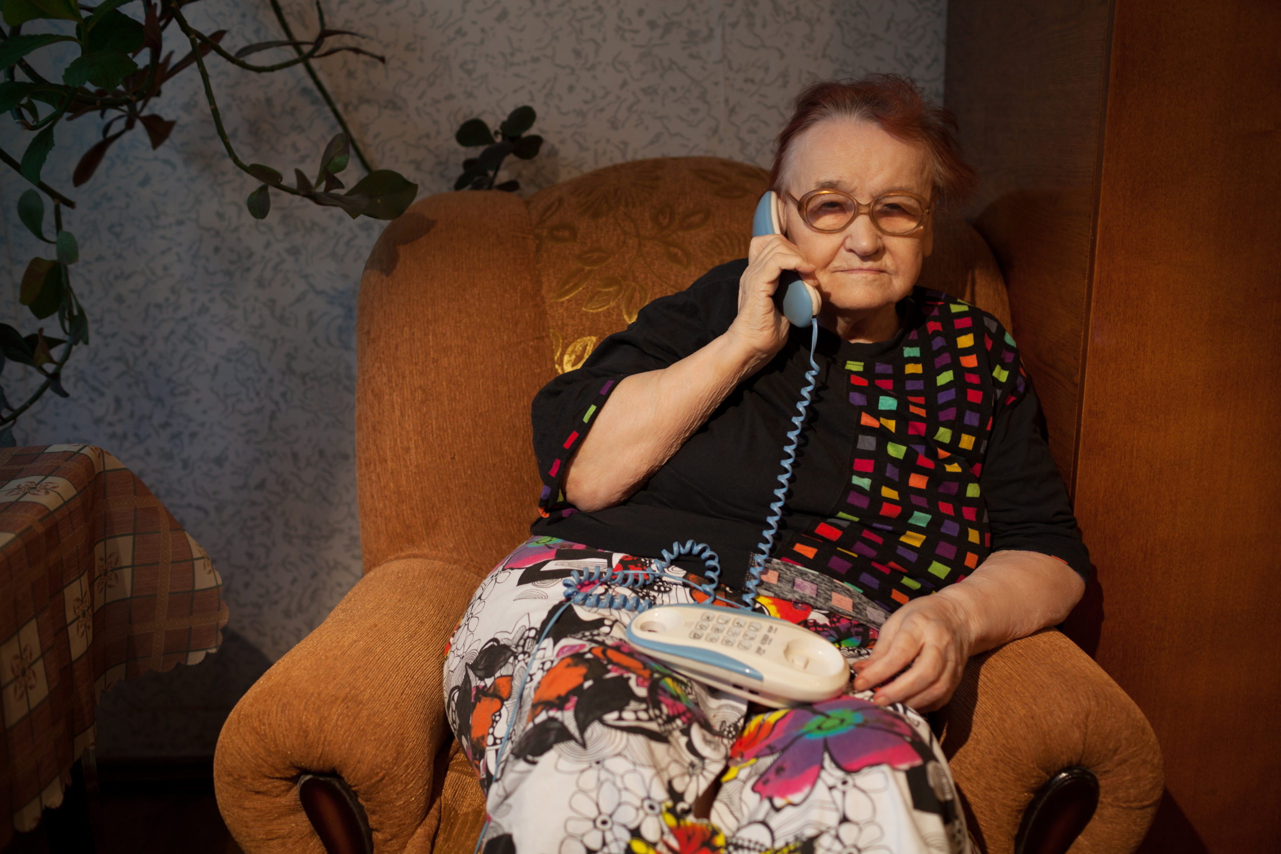 elderly woman talking on the home phone SBI 300935781 scaled
