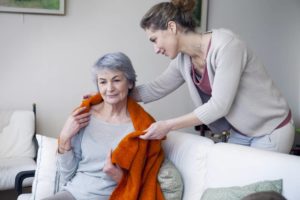 woman helping senior woman put a sweater on her shoulders