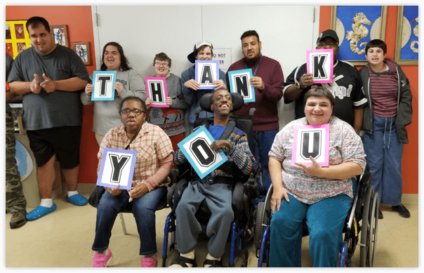 People with disabilities from the Adult Enrichment class holding up a thank you sign 