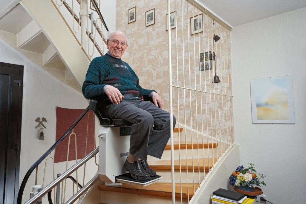 An elderly man using a stairlift in his home
